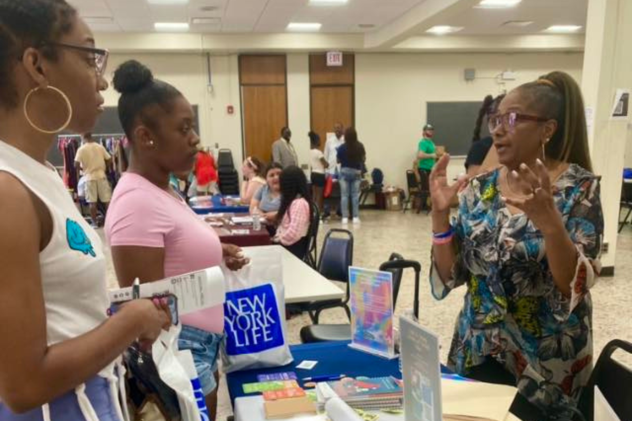 Woman with colorful shirt talking to two people at a tabling event