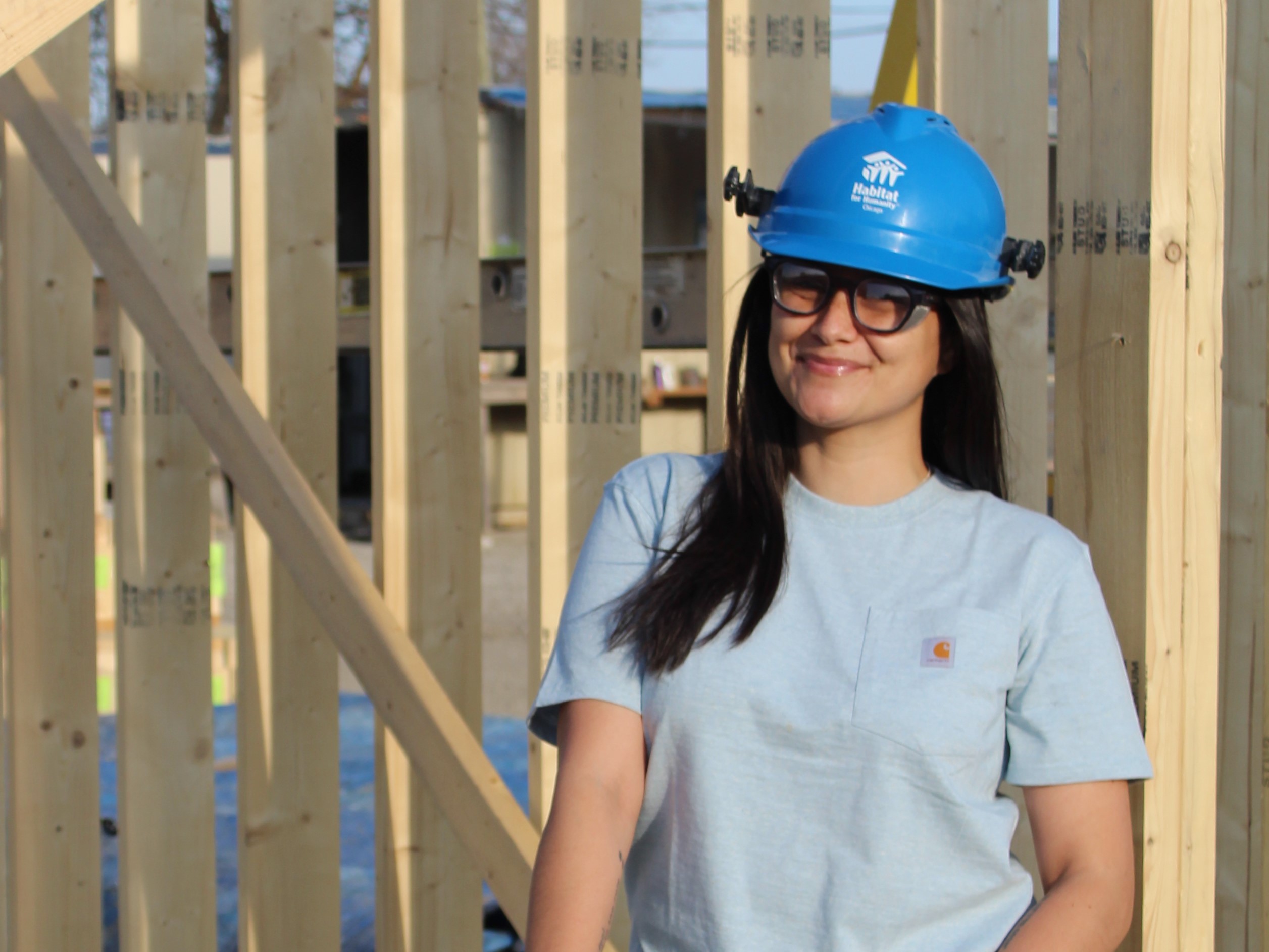Woman on construction site, wearing helmet and smiling at camera
