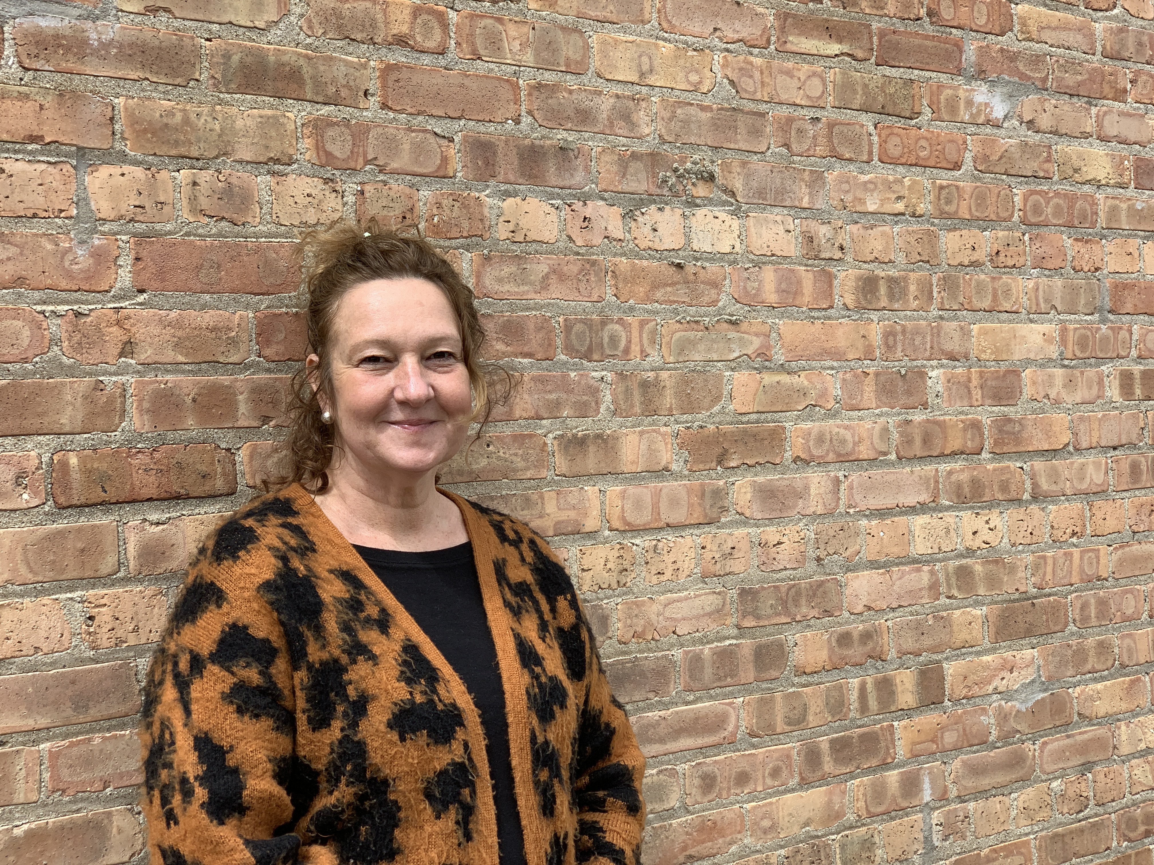 Woman smiling at camera in front of brick wall