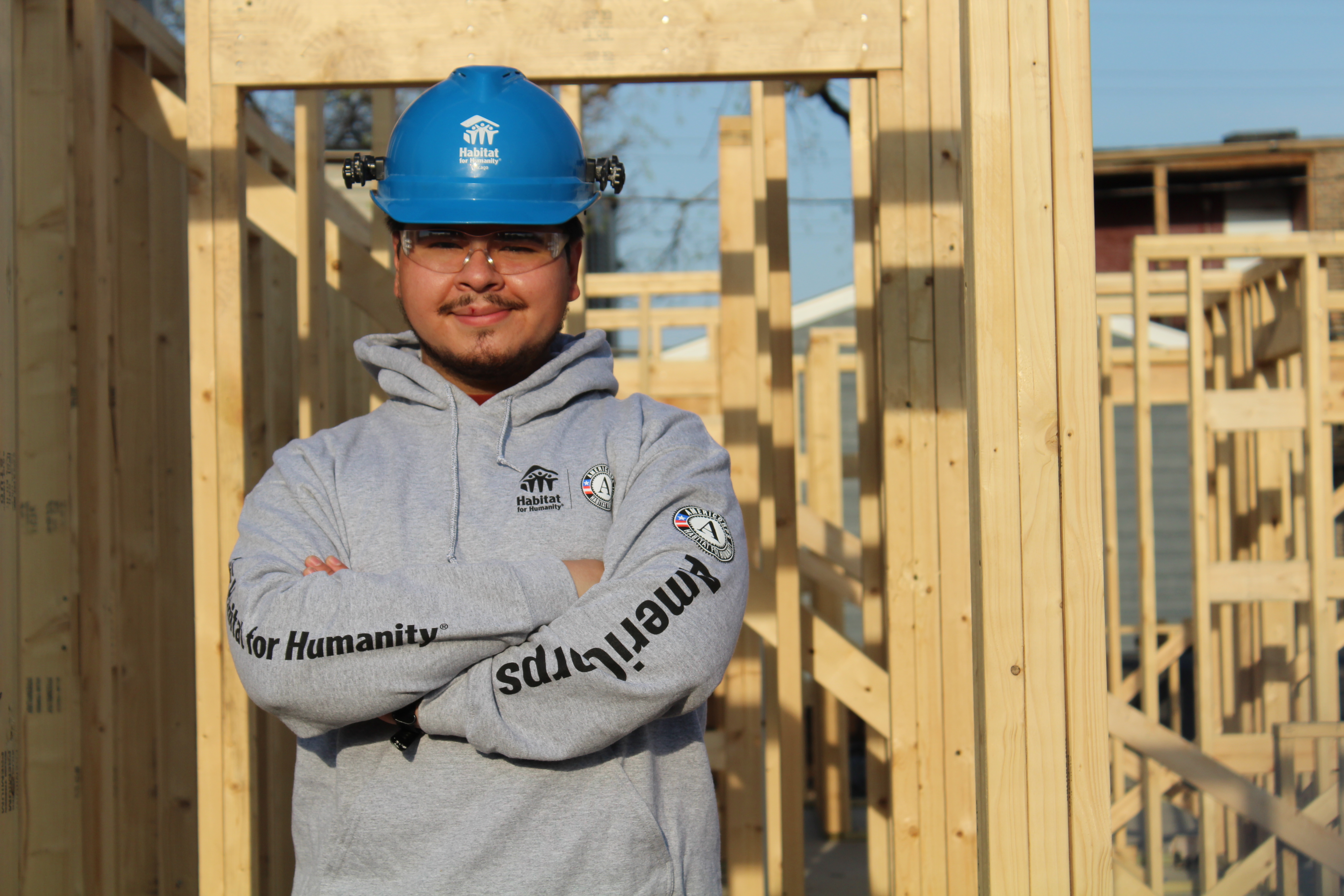 Man on construction site, wearing helmet and arms crossed