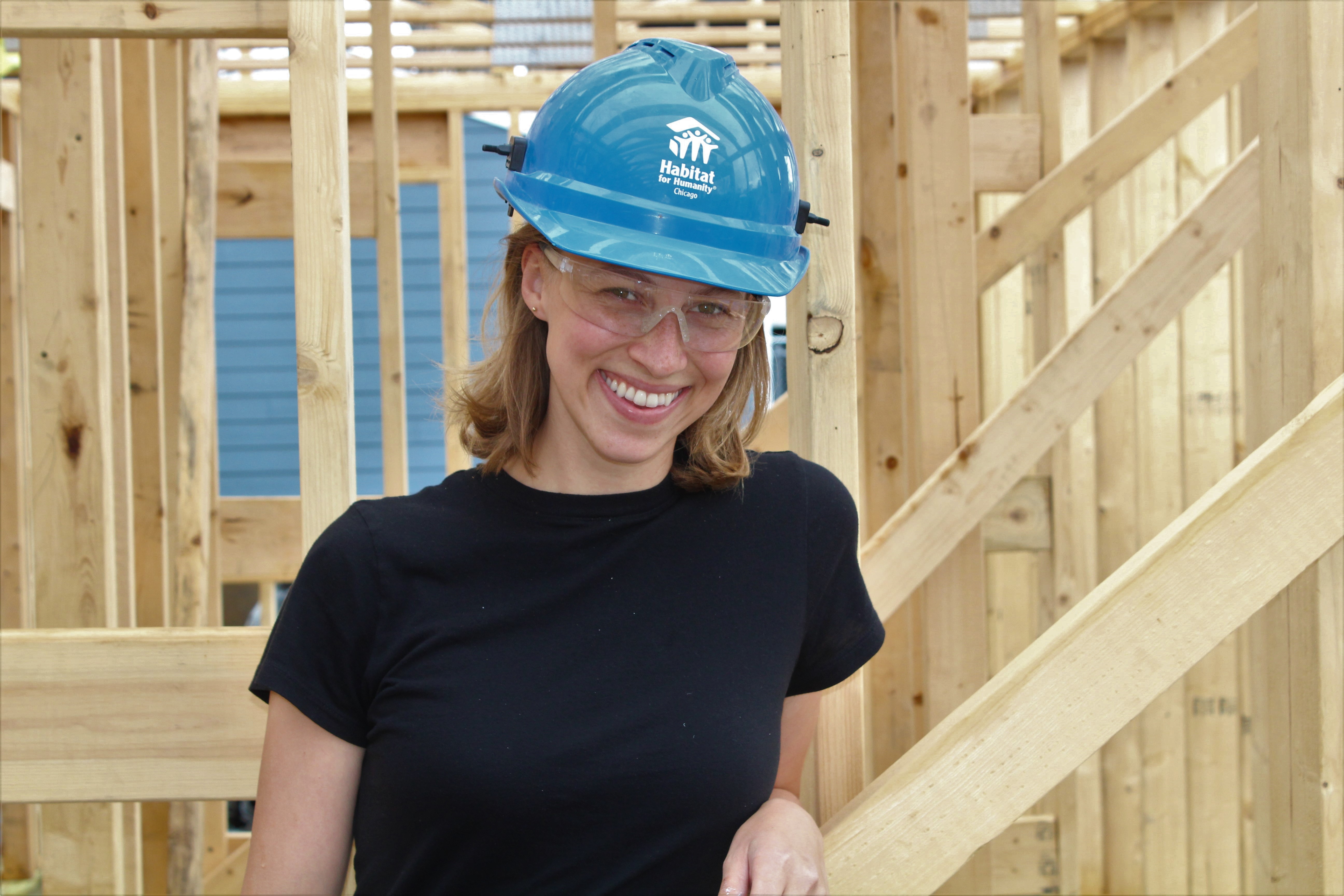 Woman on construction site, wearing helmet smiling at camera