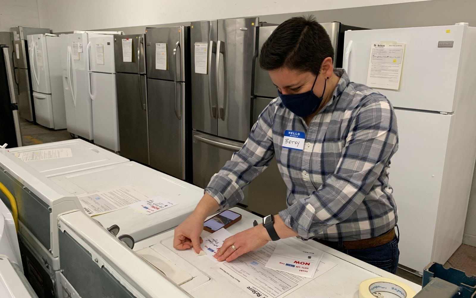 Woman with short hair placing label on appliance