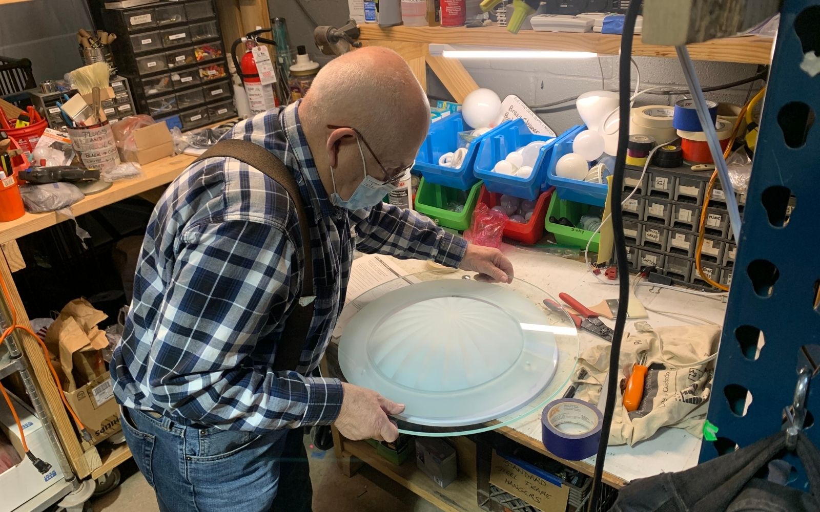 Man in a workshop, handling a light fixture