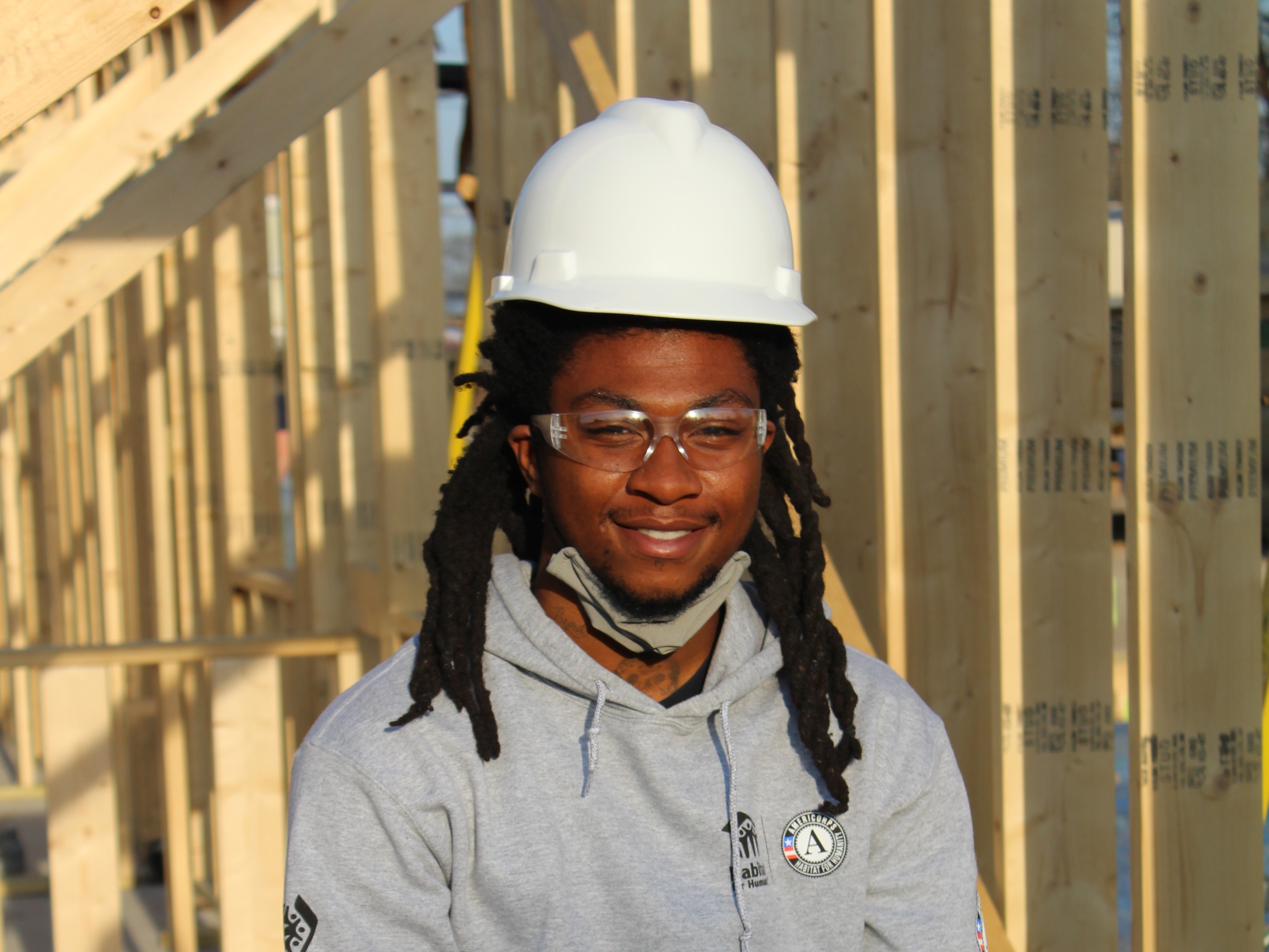 Man at construction site wearing helmet, smiling at camera