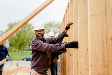 A proud volunteer raises a wall of a Habitat Chicago home 