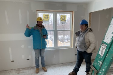 Two volunteers smile and wave on the Habitat Chicago build site 