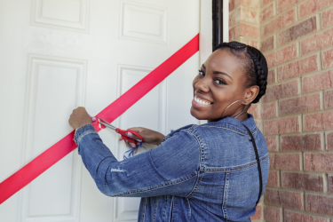 A new homeowner on the South Side of Chicago cuts the ribbon on her door