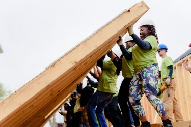 Homebuyer help raise the wall of her house