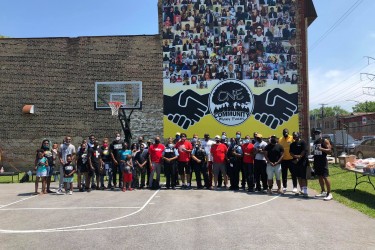 A group of community members stand in front of a newly installed wall banner