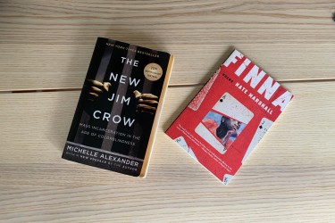 Two books on a wood table - "The New Jim Crow" and "FINNA"