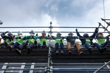 Volunteers sitting on scaffolding, posing at the camera
