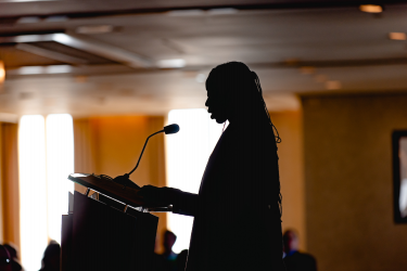 Profile silhouette of a Habitat for Humanity speaker at a podium