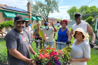 Group of Residents Smiling with Colorful Flowers Along a Fenceline