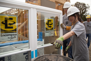 Volunteer guiding other volunteer where to put new windows on construction site