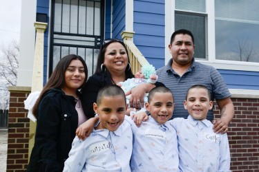 A family stands in front of their new home, celebrating their journey toward affordable homeownership