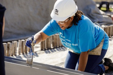 A homebuyer volunteers on the build site, constructing her future home alongside neighbors, construction staff, and community members