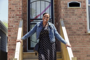 A homebuyer in front of her new, affordable, energy efficient home
