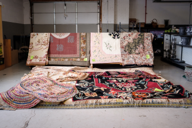 Beautiful rugs displayed hanging and lying on small platform
