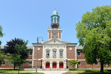 Large building with little tower in middle, framed by trees on both sides